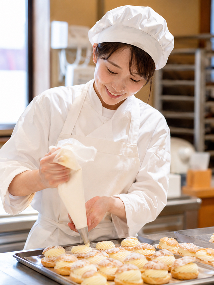 お菓子にクリームを絞る製造スタッフ